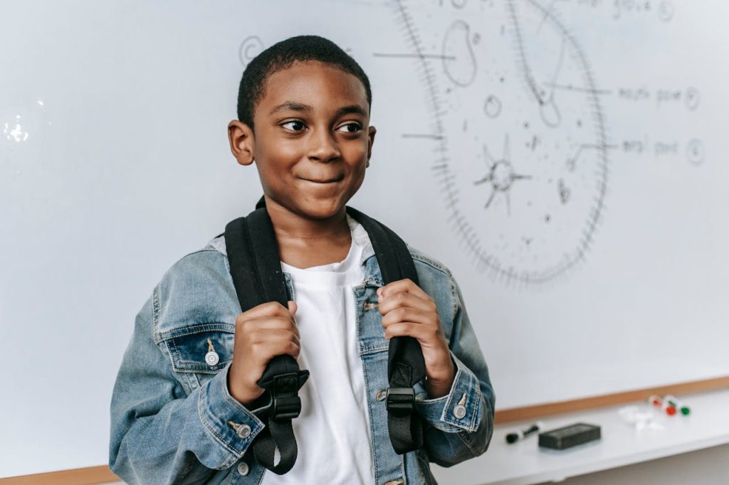 Cheerful black boy near whiteboard with scheme